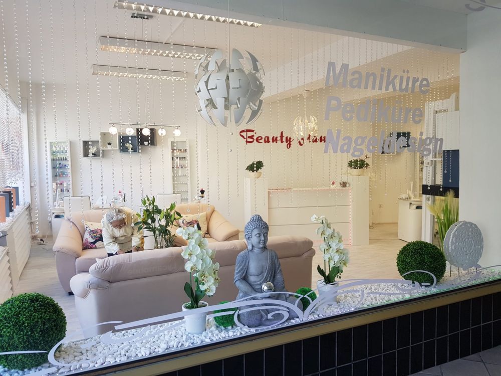 Blick durch das Schaufenster ins Studio mit Sitzecke, Empfang und dem Schriftzug Maniküre, Pediküre, Nageldesign