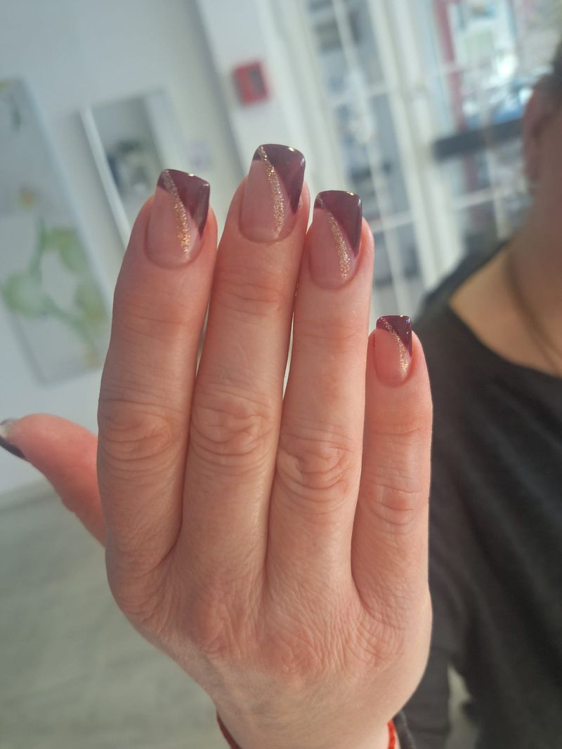 Eckige Nägel mit schräger French in Bordeaux und goldener Glitzerlinie