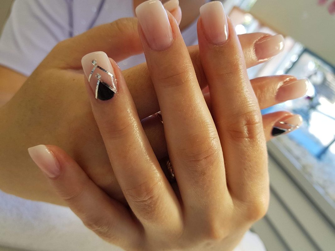 Eckige Nägel in Nude, ein Akzentnagel in Schwarz mit Silberstreifen und Steinen